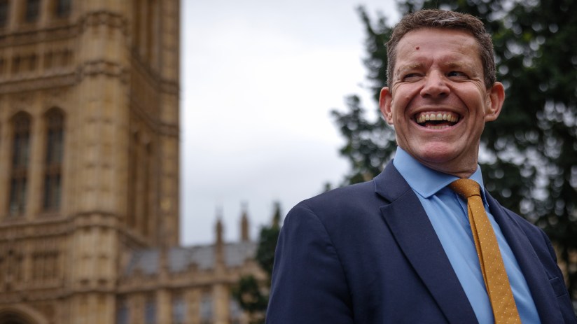 Plaid Cymru leader Rhun ap Iorwerth addressing the crowd at a public event, wearing a suit and speaking passionately