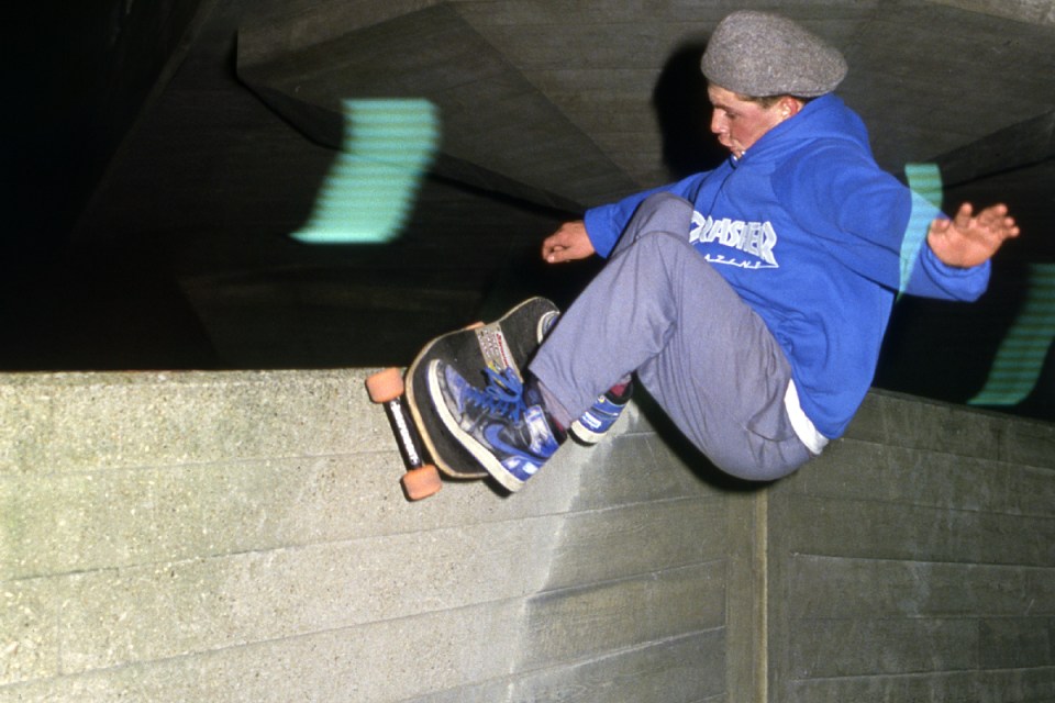 Skateboarder performing a trick in an urban skate park, highlighting skill and agility in a vibrant city setting.