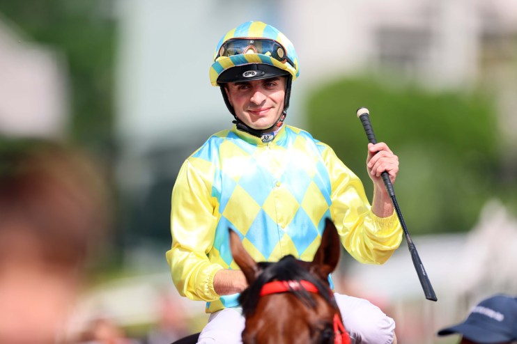 Jockey Andrea Atzeni riding a horse during a competitive race at a renowned international racing event.