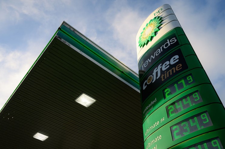 BP petrol station with green and yellow branding, multiple fuel pumps, and a canopy, set against a clear blue sky.