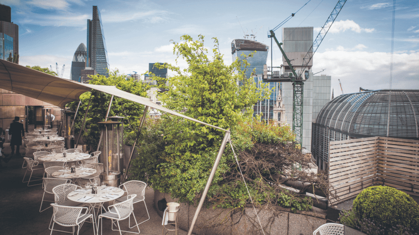 Stunning view of Londons Square Mile from a trendy rooftop bar, highlighting vibrant city skyline and chic outdoor seating