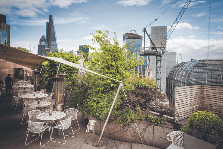 Stunning view of Londons Square Mile from a trendy rooftop bar, highlighting vibrant city skyline and chic outdoor seating