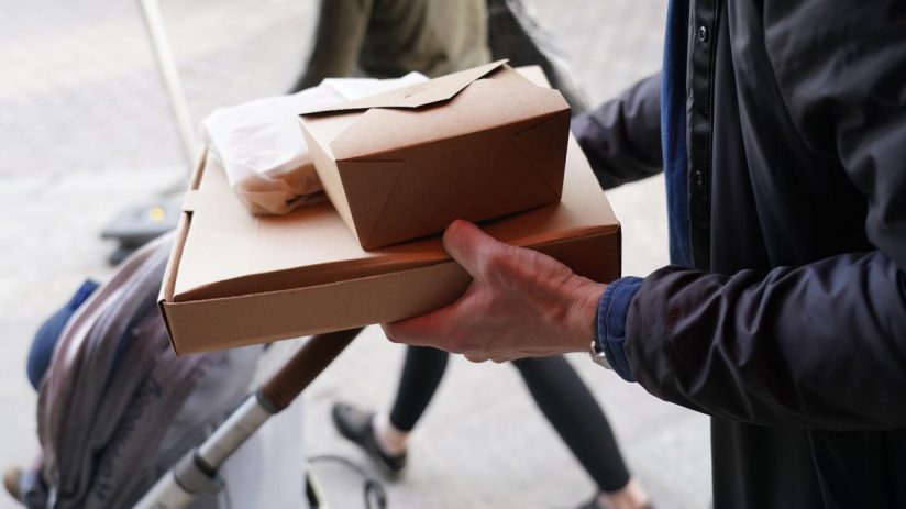 Restaurant staff handing a neatly packed doggy bag to a customer, highlighting sustainable takeout practices and customer ...