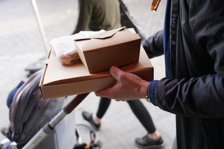 Restaurant staff handing a neatly packed doggy bag to a customer, highlighting sustainable takeout practices and customer ...