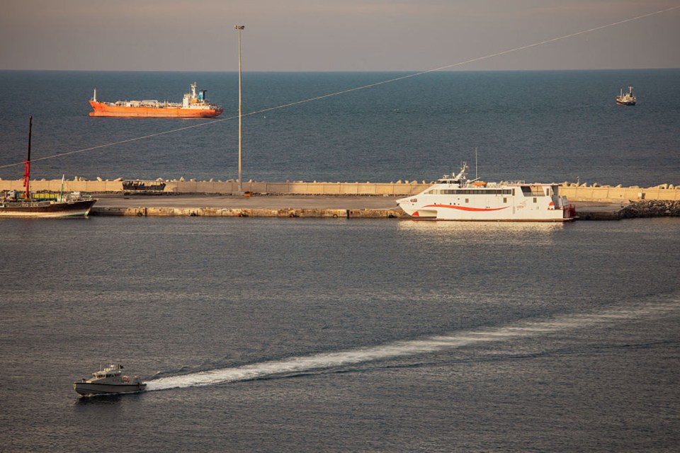 Bustling shipping activity in the Strait of Hormuz with tankers and cargo ships navigating Iranian waters.