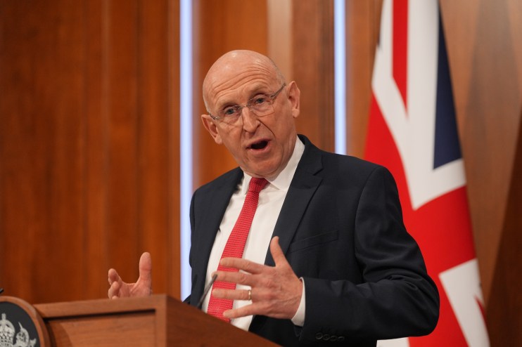 John Healey delivering a speech at a press conference, emphasizing key points on current political issues and policies.