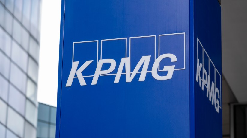 KPMG logo prominently displayed on a modern office building fa&ccedil;ade against a clear blue sky, symbolizing corporate presence