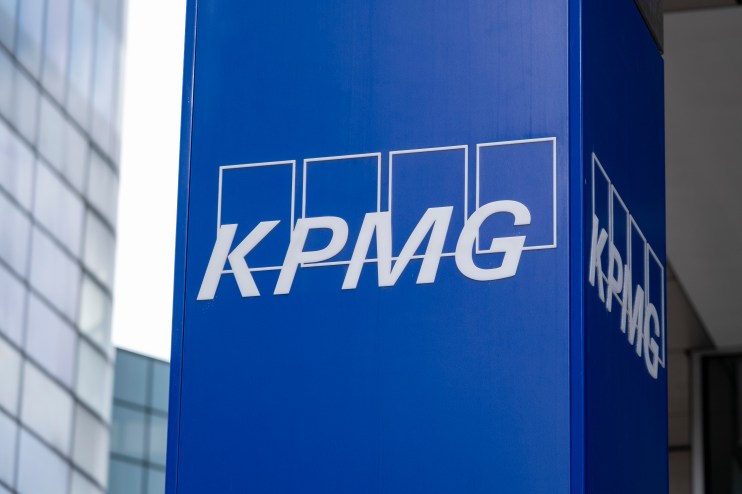 KPMG logo prominently displayed on a modern office building fa&ccedil;ade against a clear blue sky, symbolizing corporate presence
