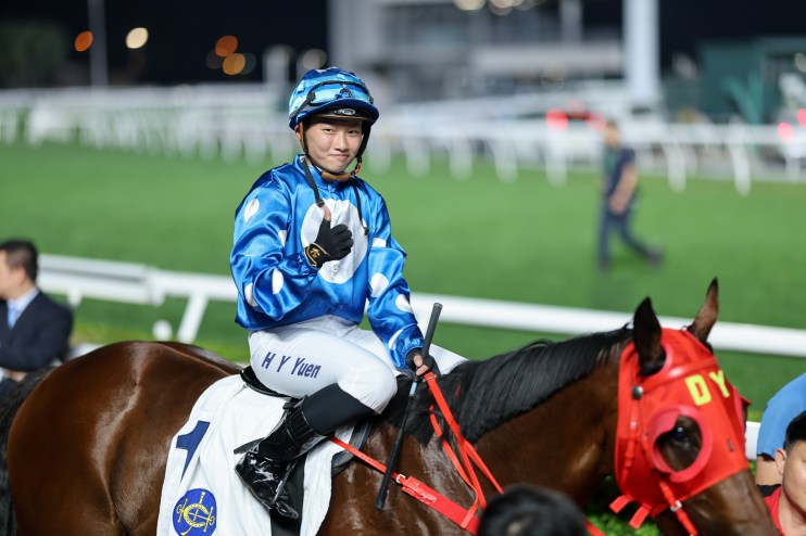 Nichola Yuen smiling during an interview, wearing a blue blazer with a cityscape background in a business news setting