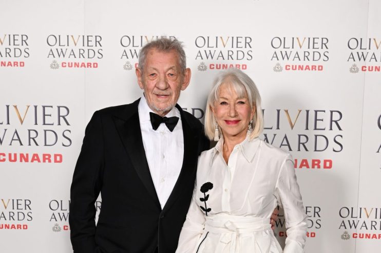 Olivier Awards ceremony stage with spotlight on presenters and audience in elegant attire, celebrating theater excellence