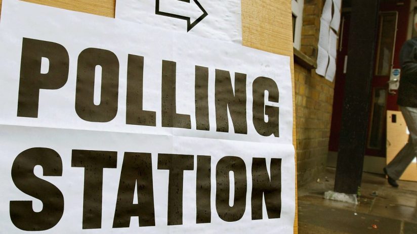 Polling station exterior with voters lining up for local election in a community setting with clear signage and ballot box...