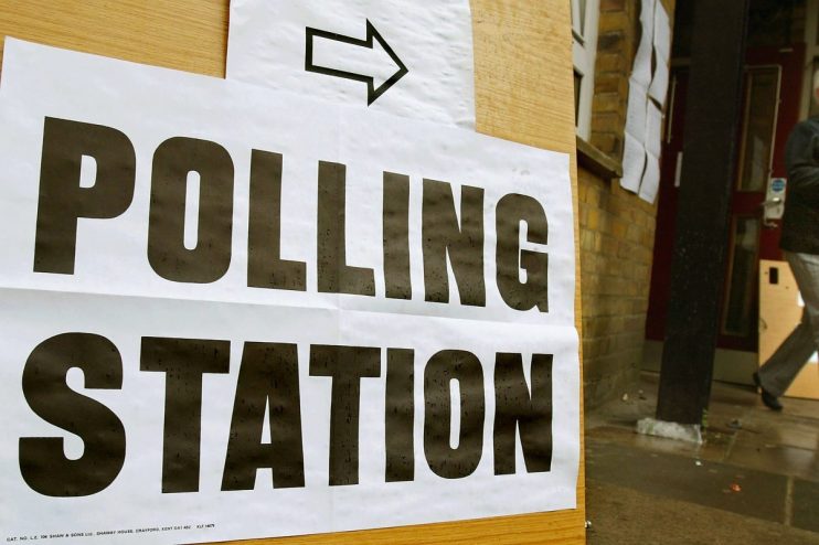 Polling station exterior with voters lining up for local election in a community setting with clear signage and ballot box...