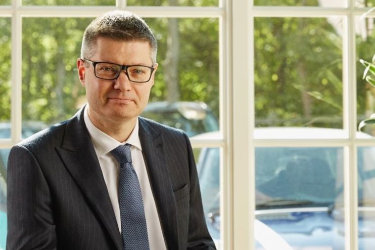 Simon Wolfson speaking at a business conference, wearing a suit and tie, addressing economic and retail industry topics