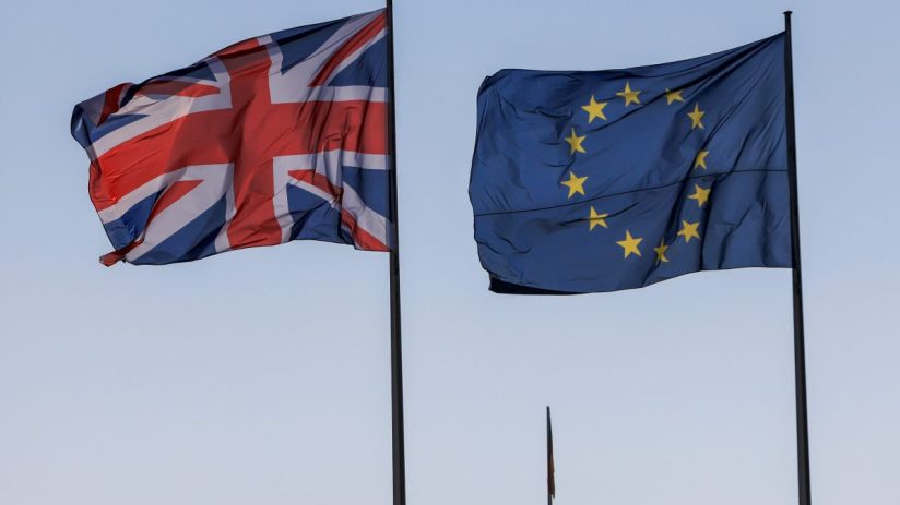 UK and EU flags intertwined, symbolizing ongoing negotiations and diplomatic relations between the United Kingdom and Euro...