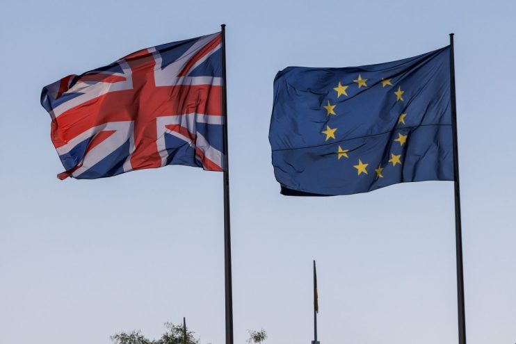 UK and EU flags intertwined, symbolizing ongoing negotiations and diplomatic relations between the United Kingdom and Euro...