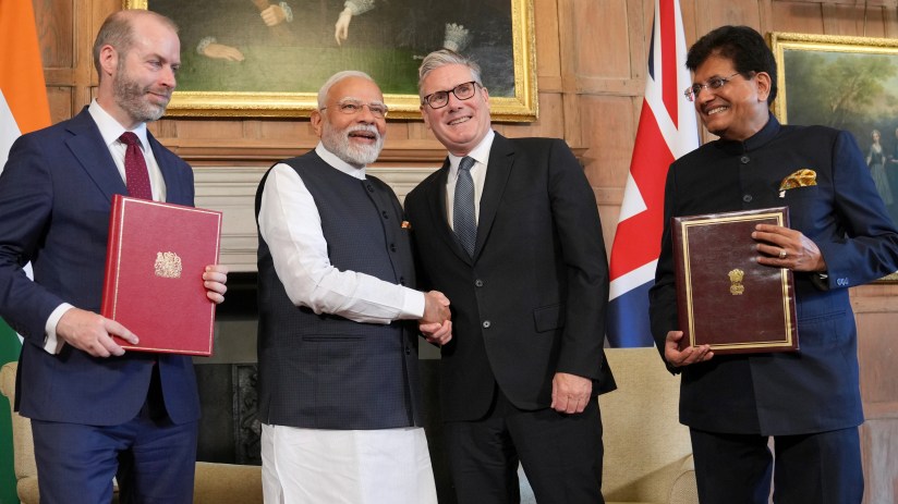 UK and India representatives signing trade agreement at formal meeting with flags and documents visible on the table