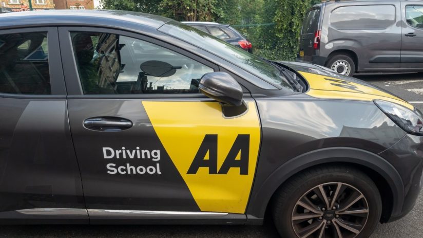 AA Driving School instructor teaching a student driver in a car, focusing on hands-on driving techniques and safety tips.