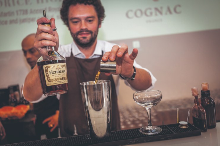 Hennessy expert crafting vibrant cocktails at the Cognac Show utilizing CYMK color techniques for mixology art