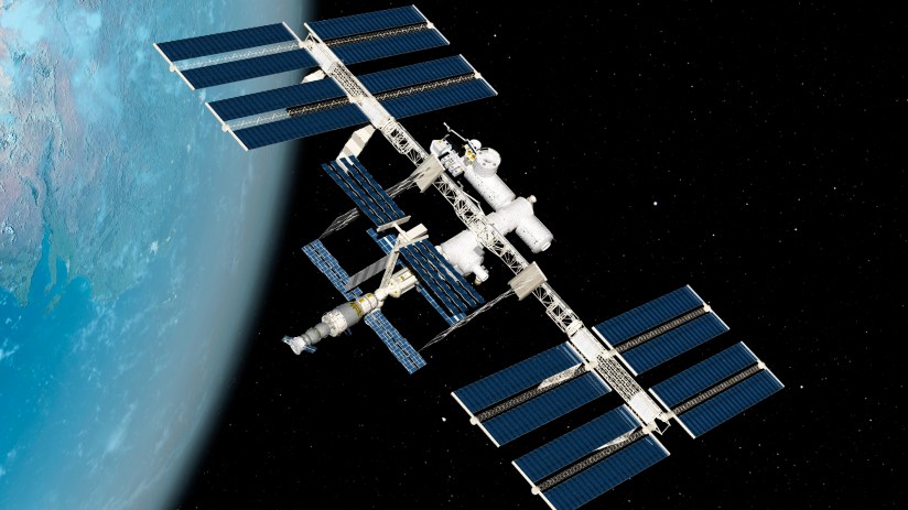 International Space Station orbiting Earth with solar panels extended against a backdrop of stars and the blue planet below