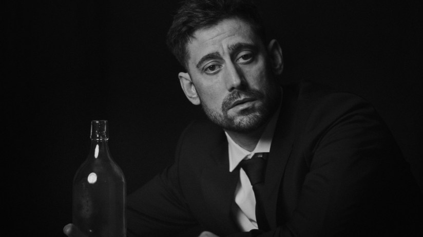 Michael Socha appearing at a public event, dressed in a suit, engaging with an audience, conveying professionalism and cha...