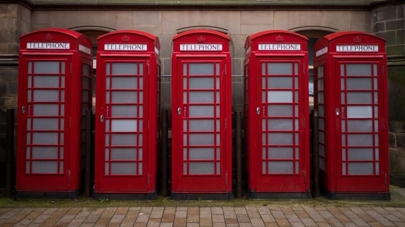 Classic red phone boxes lining a street, symbolizing British heritage and communication history.