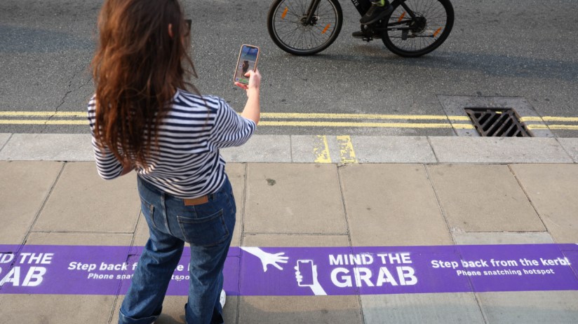 Person holds smartphone tightly in crowded urban area, highlighting phone theft concerns in bustling city environments.