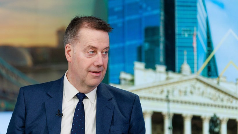 Andy Briggs, Chief Executive of Standard Life, addressing a business conference, wearing a suit and speaking at a podium.