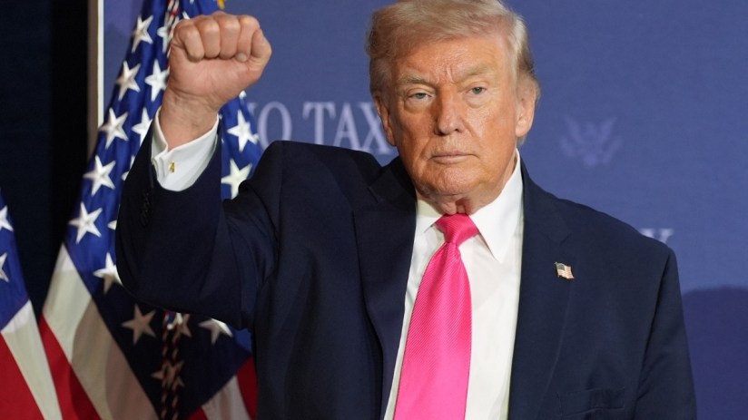 Donald Trump raising his fist in a confident gesture during a public appearance, symbolizing determination and leadership
