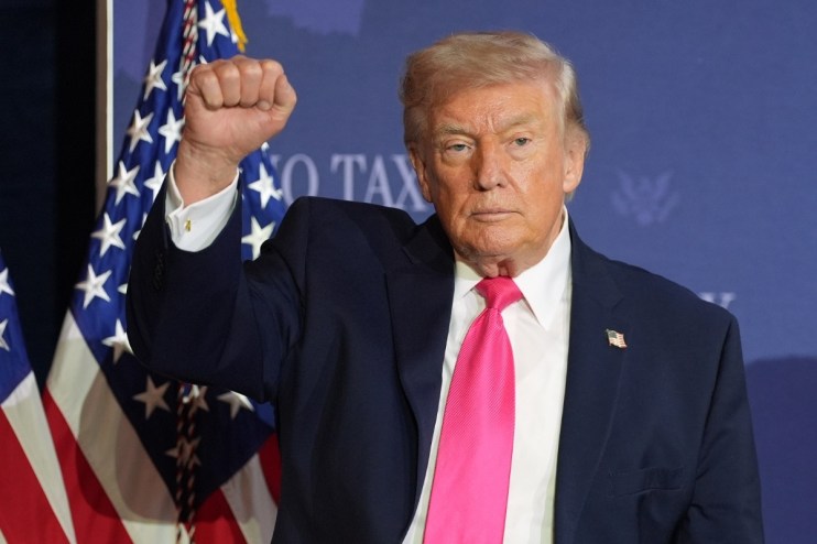 Donald Trump raising his fist in a confident gesture during a public appearance, symbolizing determination and leadership