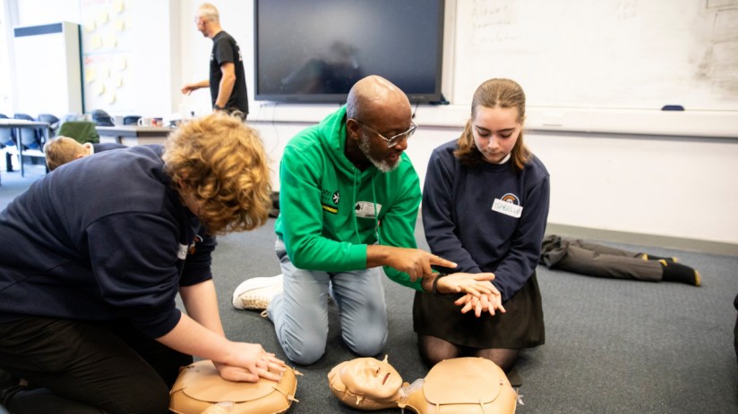 Young St. John Ambulance responders practicing first aid skills, wearing uniforms, engaging in hands-on emergency training.