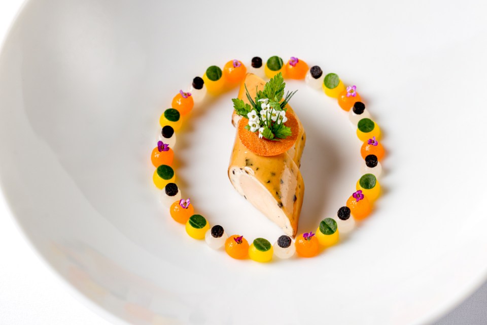 Chef Alex Dilling expertly prepares chicken dish with precision at Justin DeSouza event, showcasing culinary artistry.