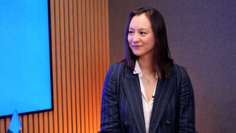 Alisha smiling confidently in professional attire, standing in a modern office environment reflecting business success.