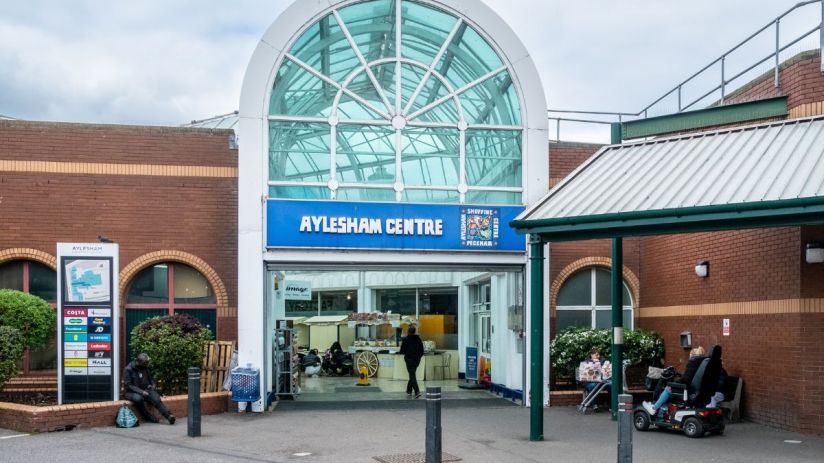 Aylesham Centre exterior view with shoppers and storefronts in bustling urban setting