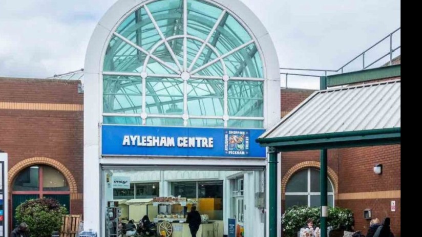 Aylesham town center bustling with shoppers and vibrant storefronts on a sunny day, highlighting community engagement