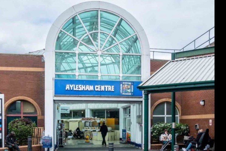 Aylesham town center bustling with shoppers and vibrant storefronts on a sunny day, highlighting community engagement