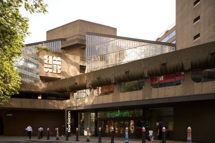 Barbican Centre exterior showcasing iconic brutalist architecture on a sunny day with people walking in the foreground
