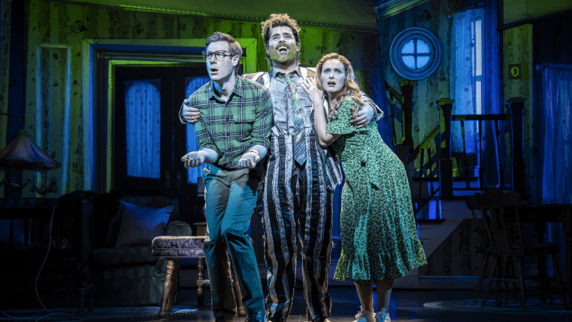 Beetlejuice musical cast performing on stage at the London production, showcasing vibrant costumes and set design