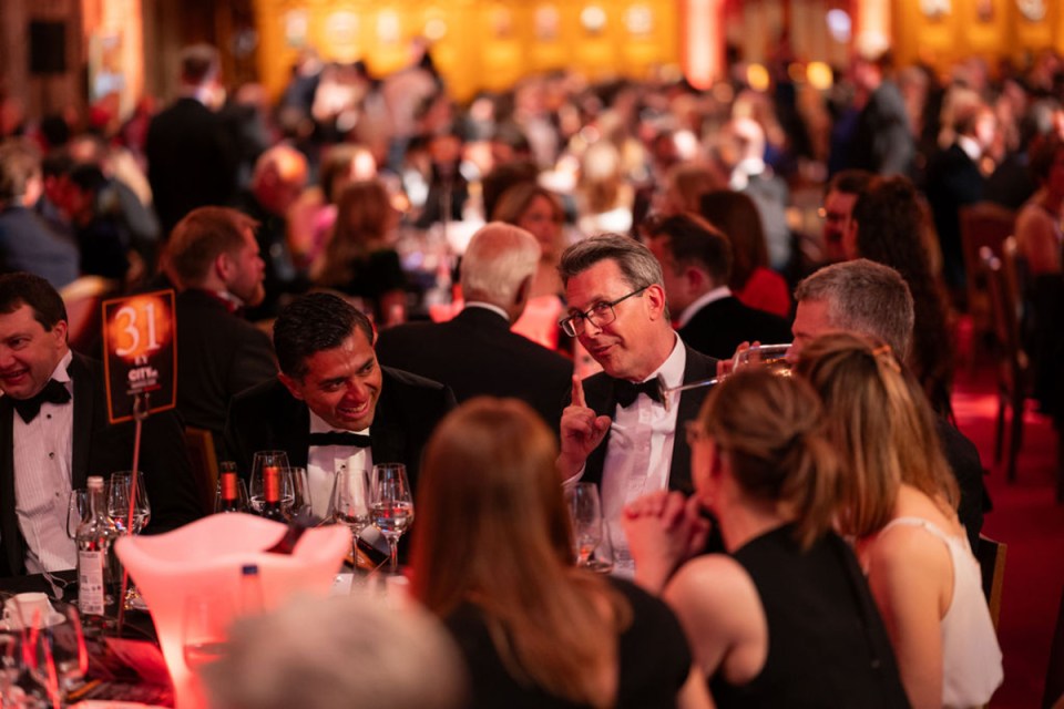 Morning Wire Awards atmosphere with elegant gala setting, attendees in formal attire, glittering lights, and award stage in the...