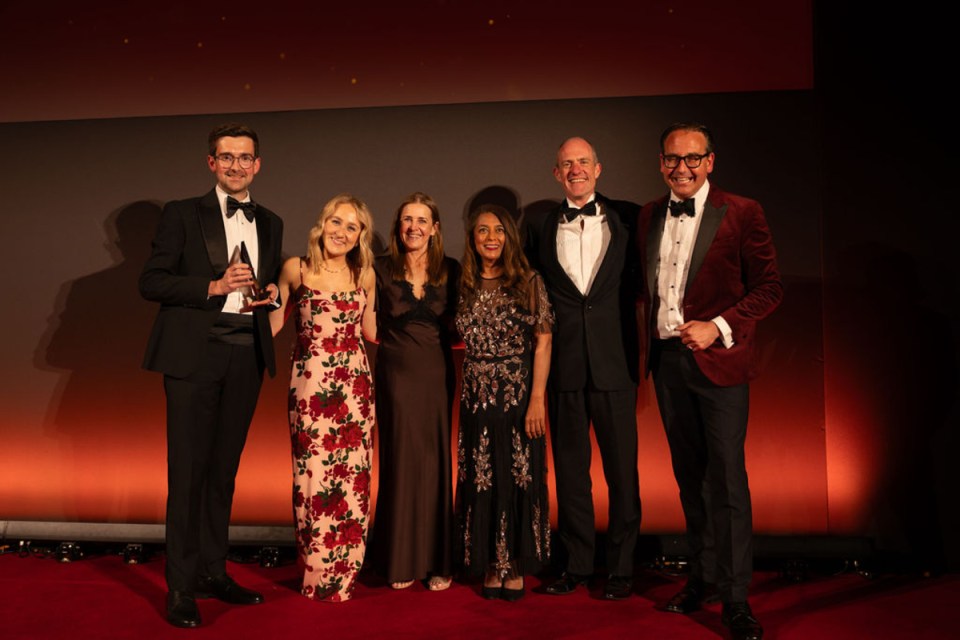 Shawbrook Bank celebrates win at Morning Wire Awards with team on stage holding trophy in formal attire