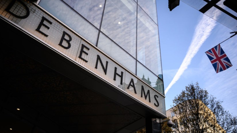 Debenhams storefront in central London showcasing seasonal window displays and iconic signage on a bustling street.
