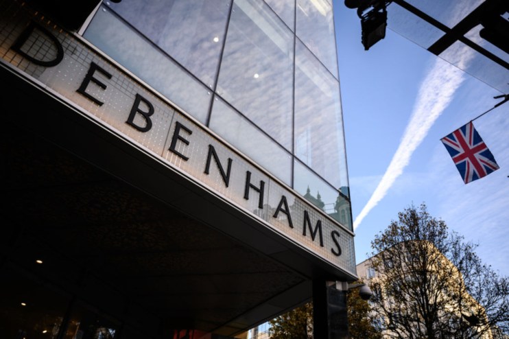 Debenhams storefront in central London showcasing seasonal window displays and iconic signage on a bustling street.