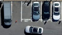 Electric vehicle charging station with multiple charging ports and cars plugged in, promoting sustainable transportation s...