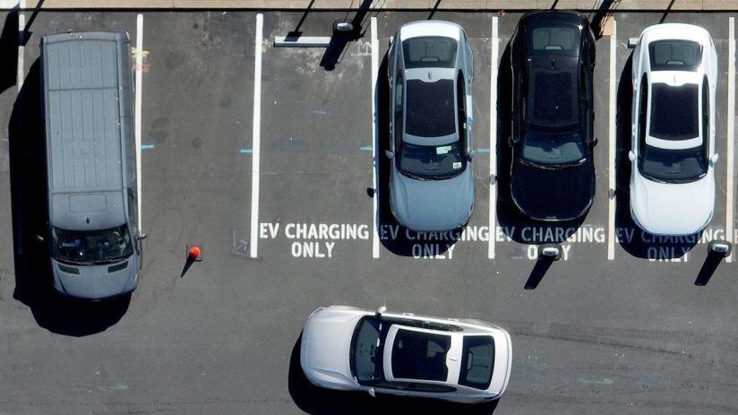 Electric vehicle charging station with multiple charging ports and cars plugged in, promoting sustainable transportation s...