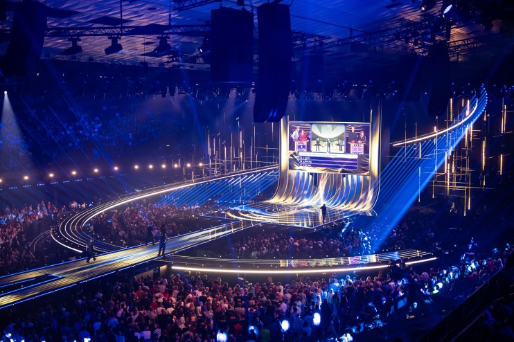 Eurovision stage with vibrant lights and performers captivating an enthusiastic audience during the live music competition.