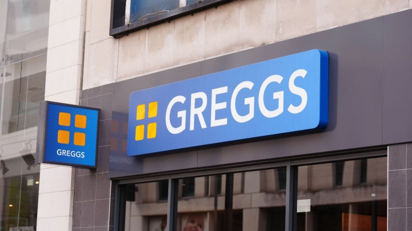 Greggs storefront with bright signage, bustling with customers, showcasing seasonal pastries and popular baked goods