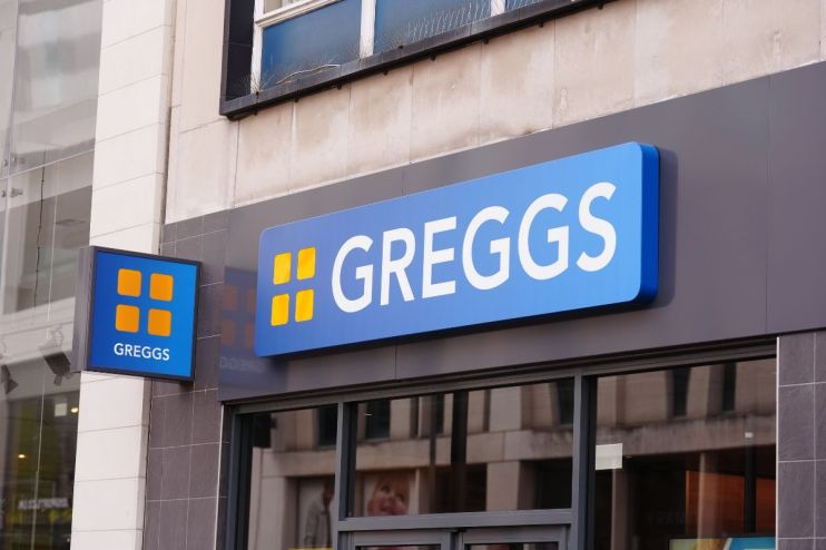 Greggs storefront with bright signage, bustling with customers, showcasing seasonal pastries and popular baked goods