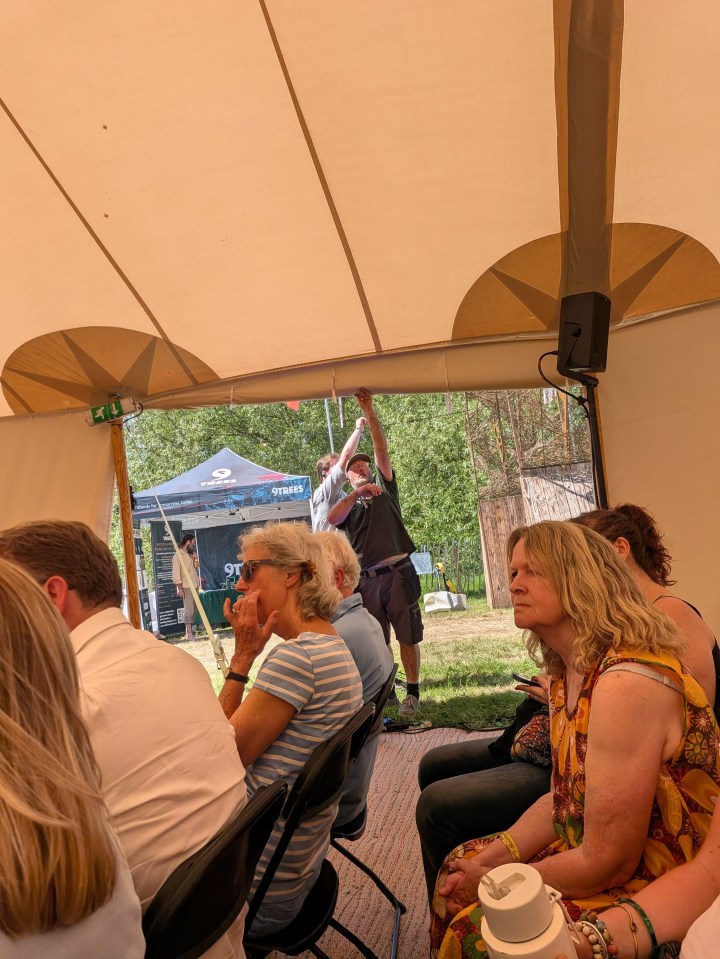 Open HTLGI tent flap with festival attendees gathering outside under a clear sky