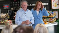 Keir Starmer and Rachel Reeves discuss the Great British Summer Savings scheme at a press conference podium with banners b...