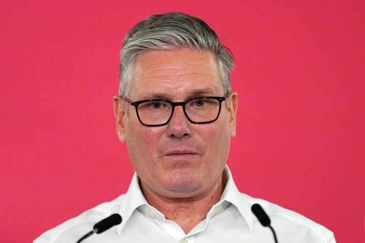 Keir Starmer delivering a speech on May 11, addressing political issues, in a formal setting with an audience.