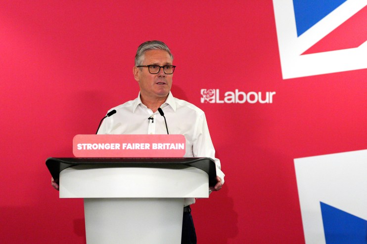 Keir Starmer delivering a speech at a podium, addressing audience with focused expression, highlighting key political points